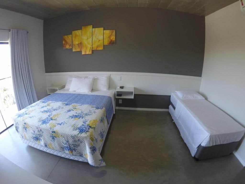 Quarto simples, com uma cama de casal com duas mesas de cabeceira, e uma cama de solteiro, na Luz da Lua Pousada