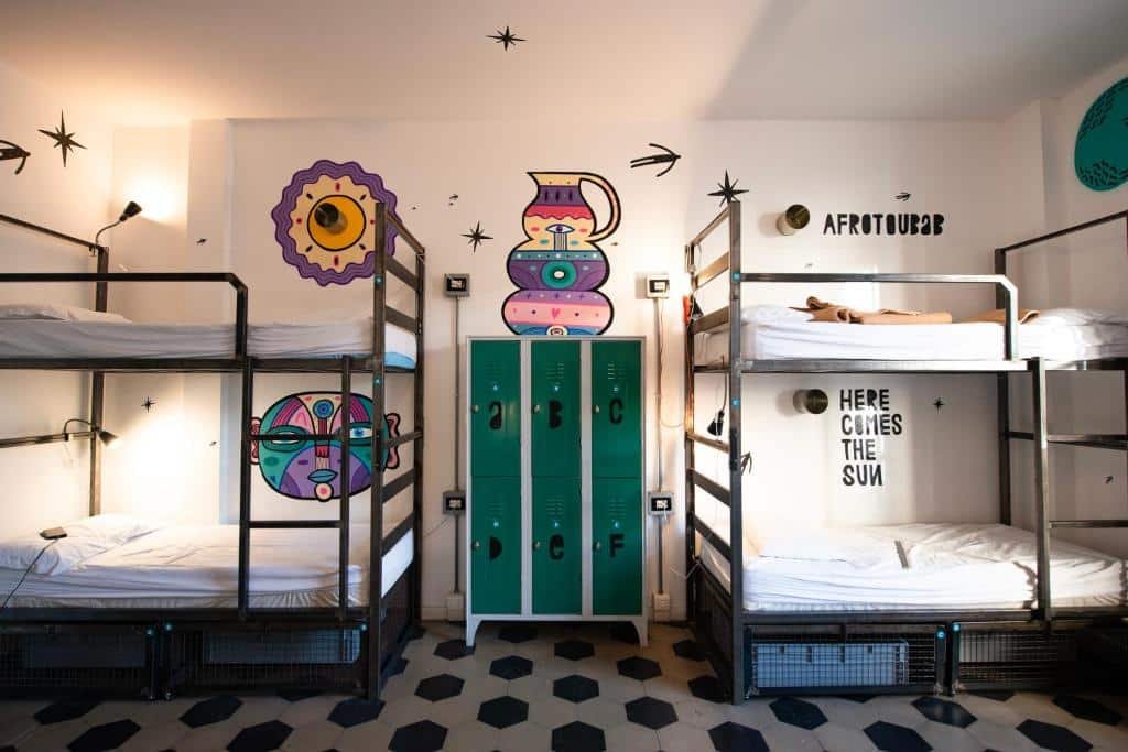 Quarto compartilhado no Madama Hostel & Bistrot com duas beliches de ferro, entre elas, há um armário com seis portinhas, e há alguns desenhos coloridos nas paredes