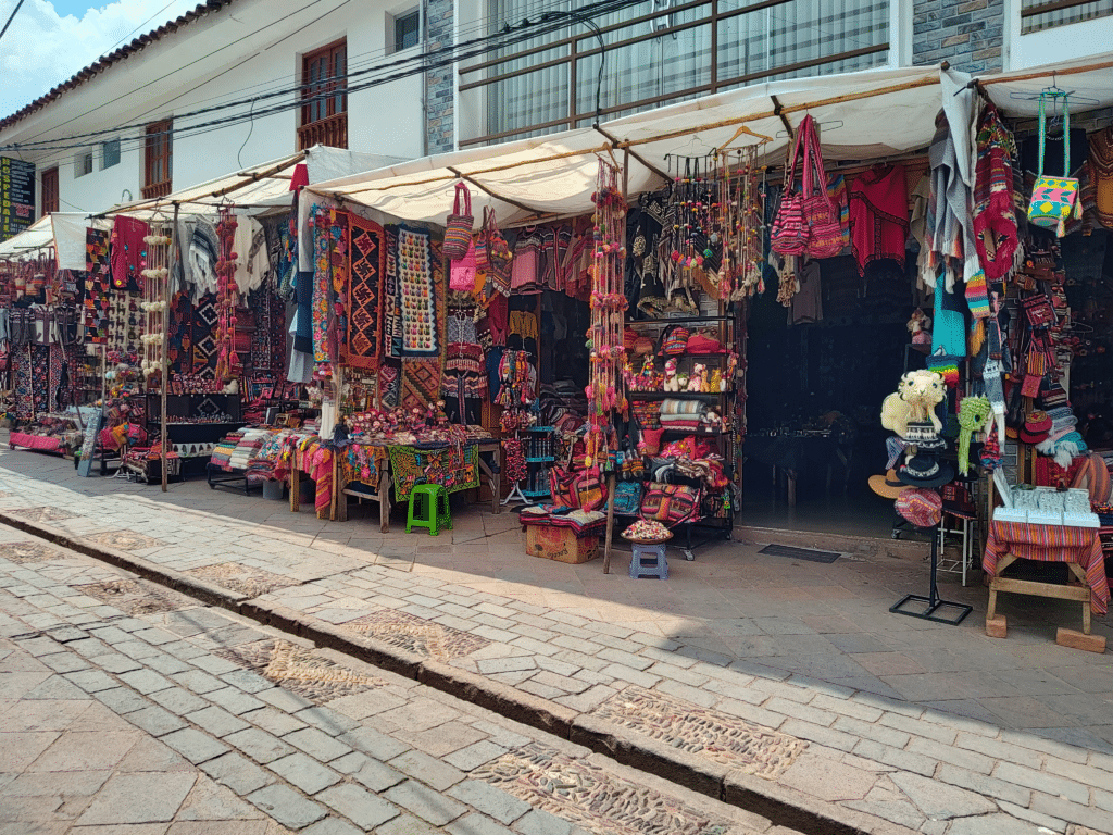 vista frontal de várias lojas, lado a lado, na rua em Pisaq, uma das muitas coisas o que fazer no Vale Sagrado dos Incas. Há muitos tecidos e produtos artesanais feitos em lã. 