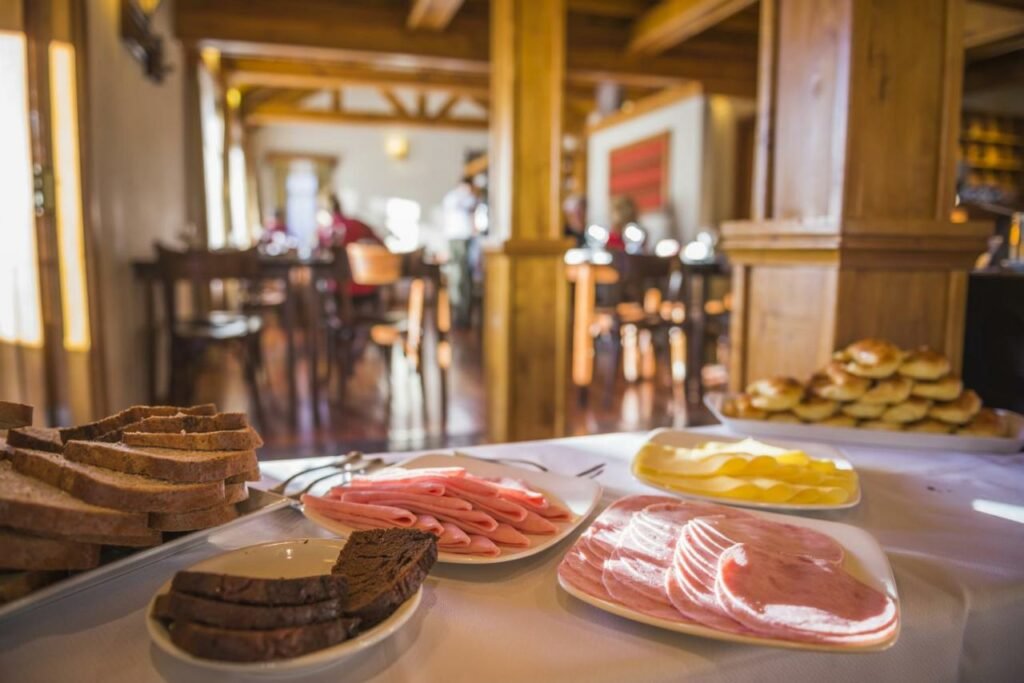 Mesa de café da manhã do Hosteria Senderos  com frios e pães em cima.