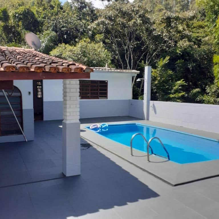 Foto da área de lazer no Meu pedacinho de chão. Há uma varanda coberta na esquerda, e na direita há uma piscina com escada.