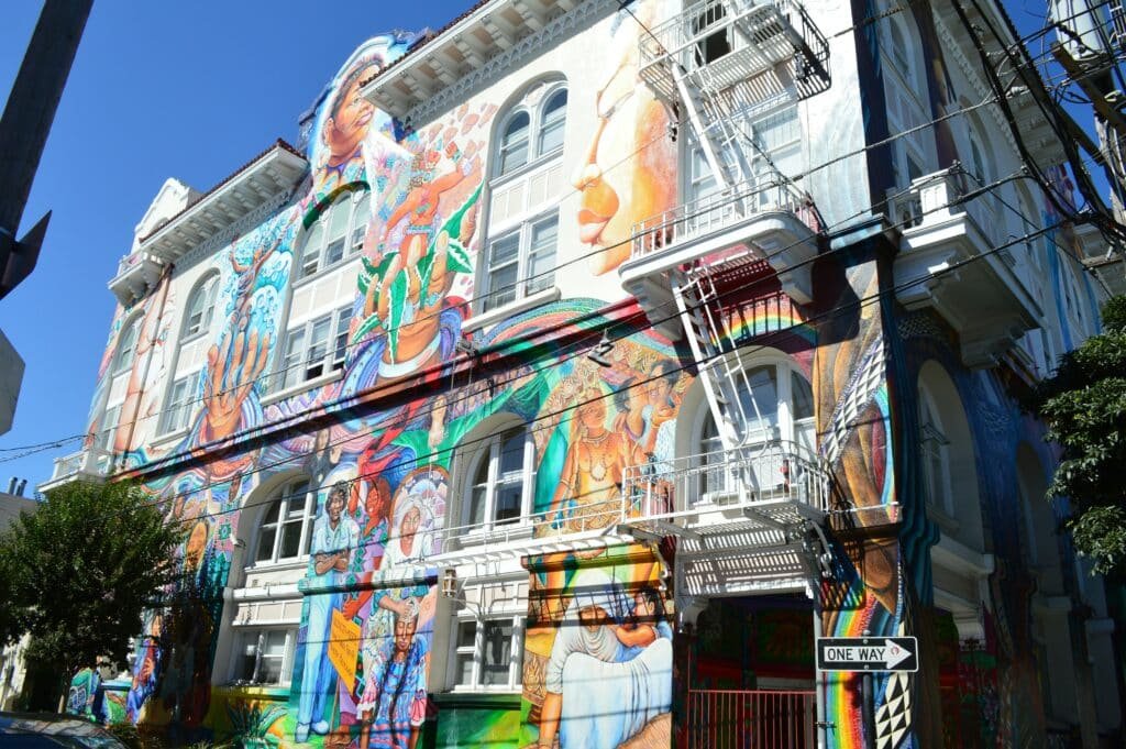 Mural em uma construção no bairro Mission District. As pinturas são bem coloridas e variadas, com mulheres, crianças e muito mais.
