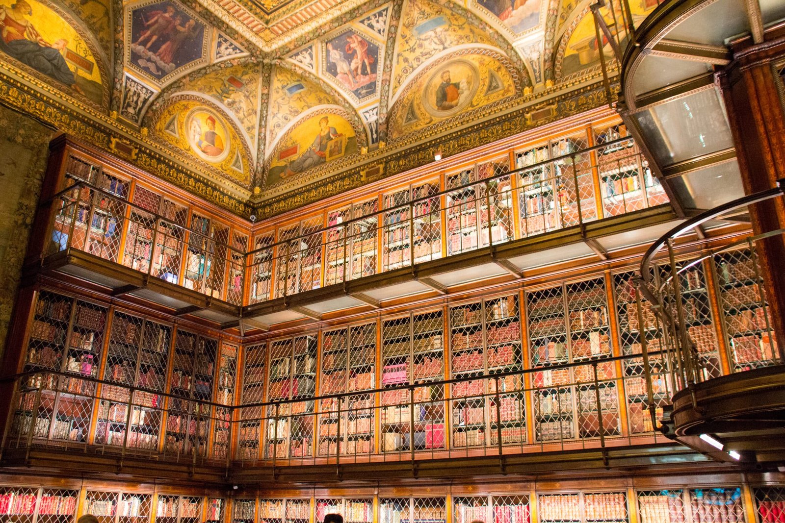 Morgan Library & Museum com tetos ornamentados e duas fileiras de estantes cheias de livros, fechadas por treliças de metal. Imagem para ilustrar post sobre museus em Nova York.