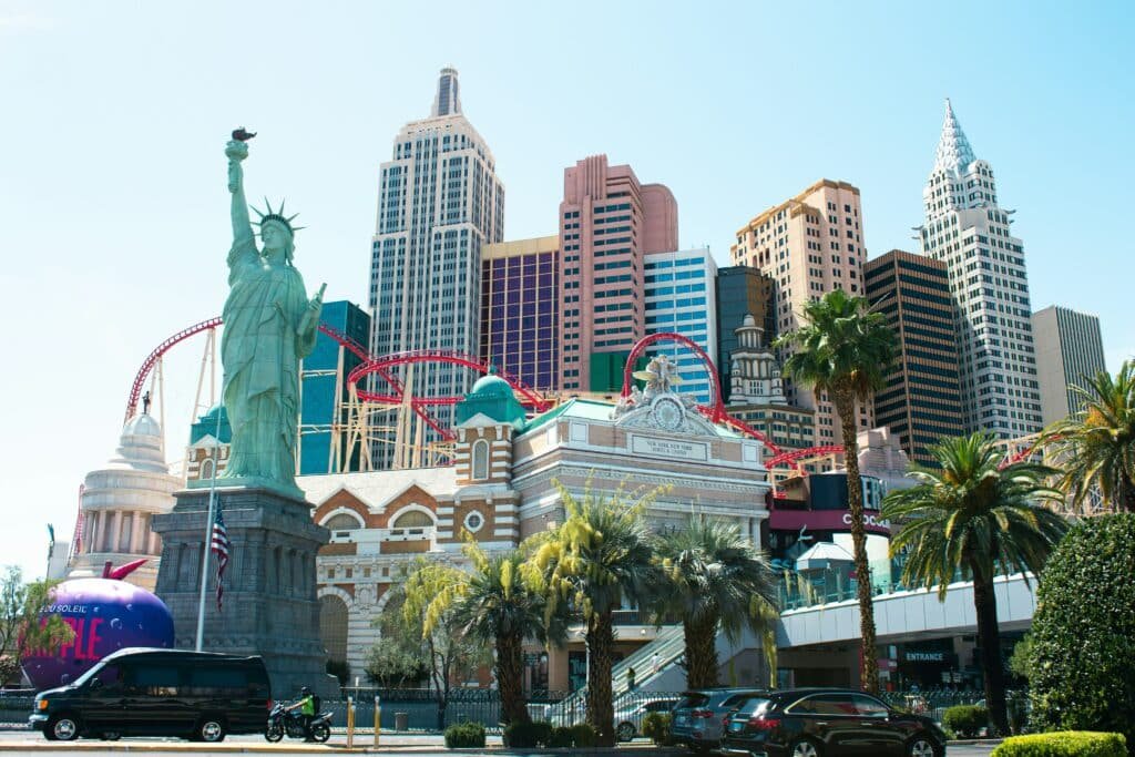 Estrutura externa do hotel New York New York. Uma cópia da estátua da liberdade fica a frente e ao redor dela estão vários outros edíficos (cópias) de Nova York. Uma montanha-russa passa pelo meio de tudo. Foto para a lista de pontos turísticos em Las Vegas.