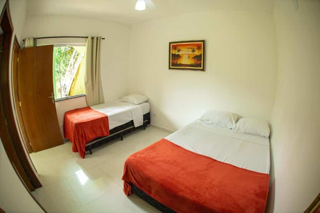 Quarto do Pacífico Sul Suítes. Uma cama de casal do lado direito e uma cama de solteiro do lado esquerdo. No fundo uma janela e a porta. Foto para ilustrar post sobre airbnb em Ubatumirim.