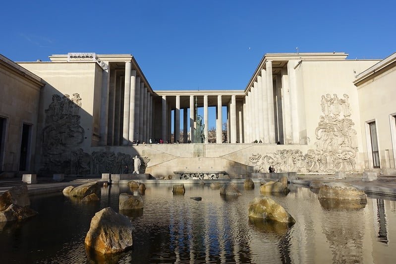 Vista frontal do Palais de Tokyo, em Paris, mostrando sua arquitetura moderna e um espelho d