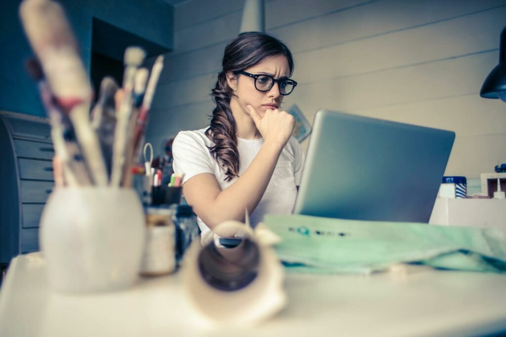 Uma mulher com uma expressão pensativa enquanto olha para tela de um notebook