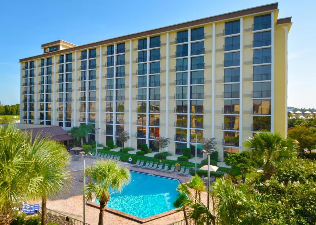piscina e fachada do Rosen Inn Closest to Universal, um dos hotéis na International Drive, em Orlando com algumas palmeiras ao redor e janelas espelhadas