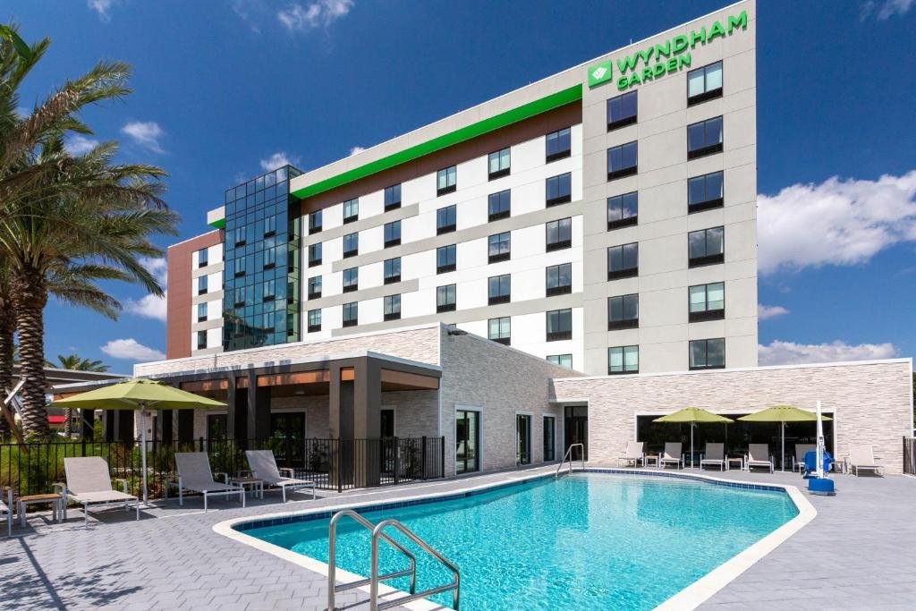 fachada do Wyndham Garden Orlando Universal / I Drive com detalhes em verde claro e uma piscina retangular abaixo no Wyndham Garden Orlando Universal / I Drive, um dos hotéis na International Drive em Orlando