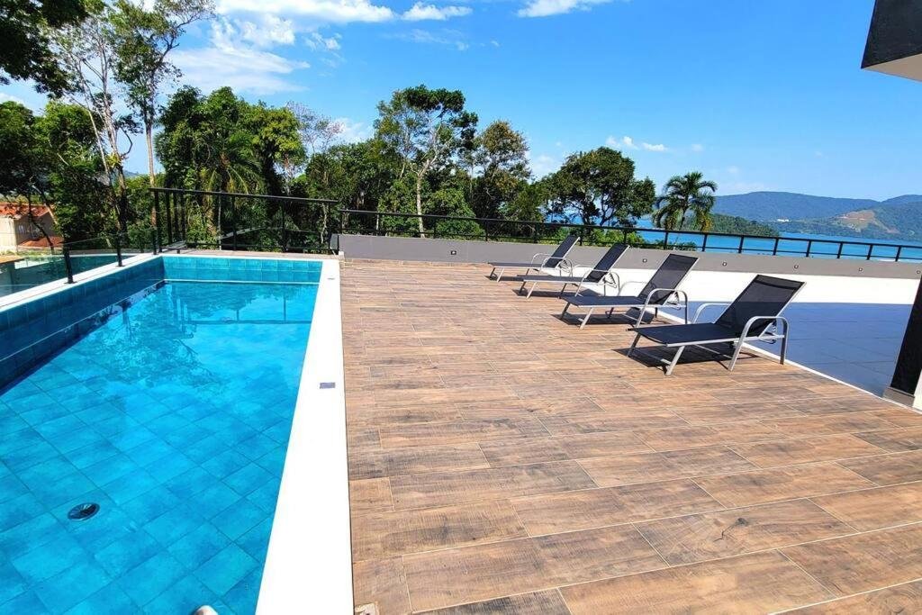 Piscina do Apê na praia da Lagoinha a 400m da praia durante o dia com piscina do lado esquerdo da imagem e do lado direito cadeiras.