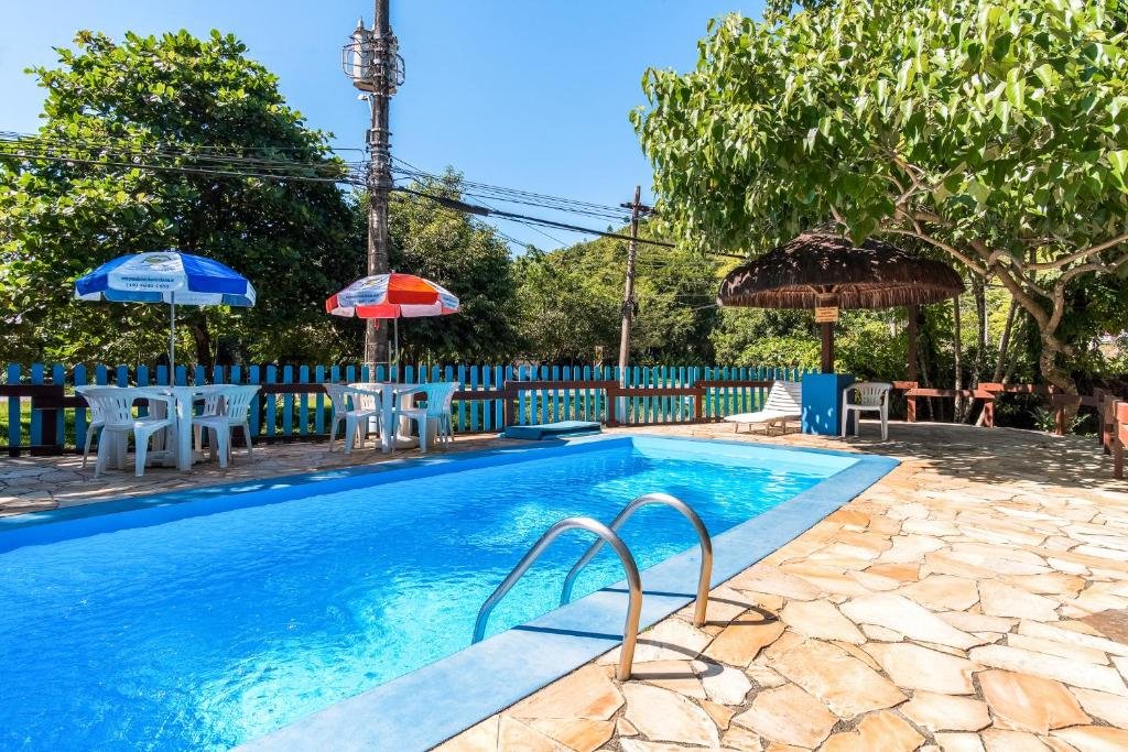 Piscina em Pousada Sanremo Inn, com um deck cercado por cadeiras e guarda-sóis, para representar pousadas na Praia das Toninhas