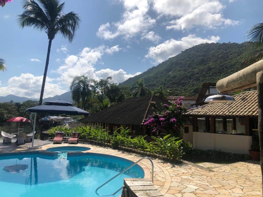 Área externa da Pousada Una, com muita vegetação ao redor, uma piscina redonda, com mesas e cadeiras ao redor