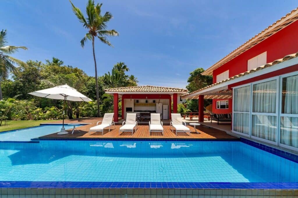 Piscina ao ar livre da Quintas de Sauípe – Casa D13 com piscina a frente e ao fundo cadeiras na beira da piscina e do lado direito da imagem a estadia.