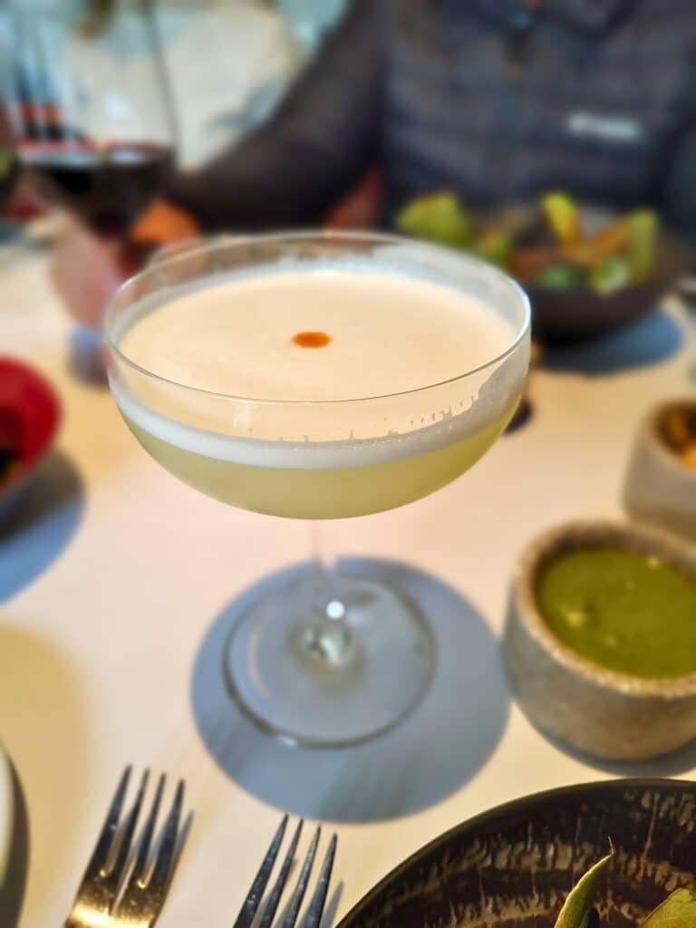 uma taça arredondada de pisco sour, uma bebida típica peruano