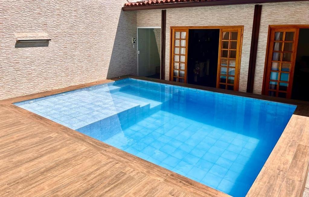 Imagem da piscina da Casa Chalé na Barra da Tijuca Com Piscina Próximo a Praia durante o dia localizada no centro da imagem e do lado direito da piscina a acomodação.