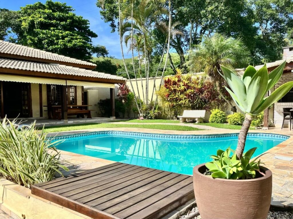 Piscina ao ar livre da Casa de temporada estilo rústico durante o dia com a piscina a frente e do lado esquerdo a propriedade. 