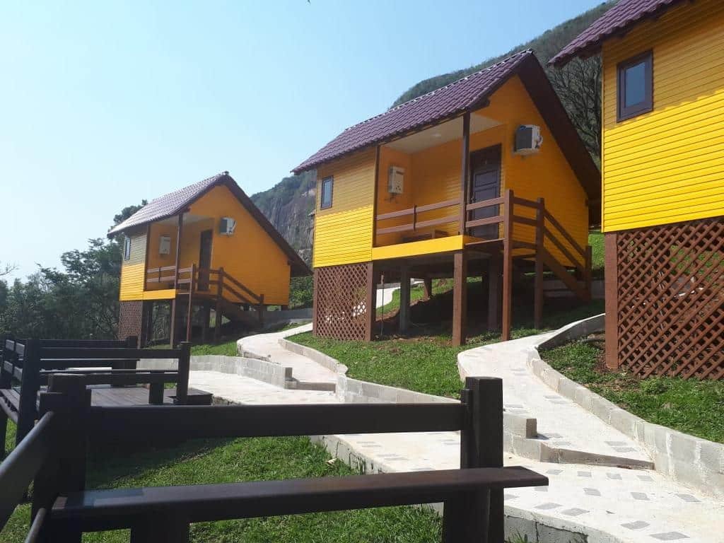 Vista das casas da Pousada Bugio da Serra. Há três estruturas acessíveis por escadas de madeira.