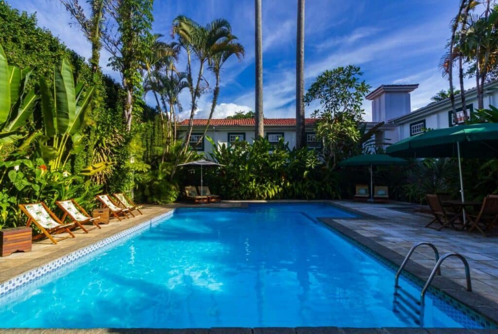 Piscina da Pousada do Príncipe com muita vegetação ao redor e espreguiçadeiras no deck