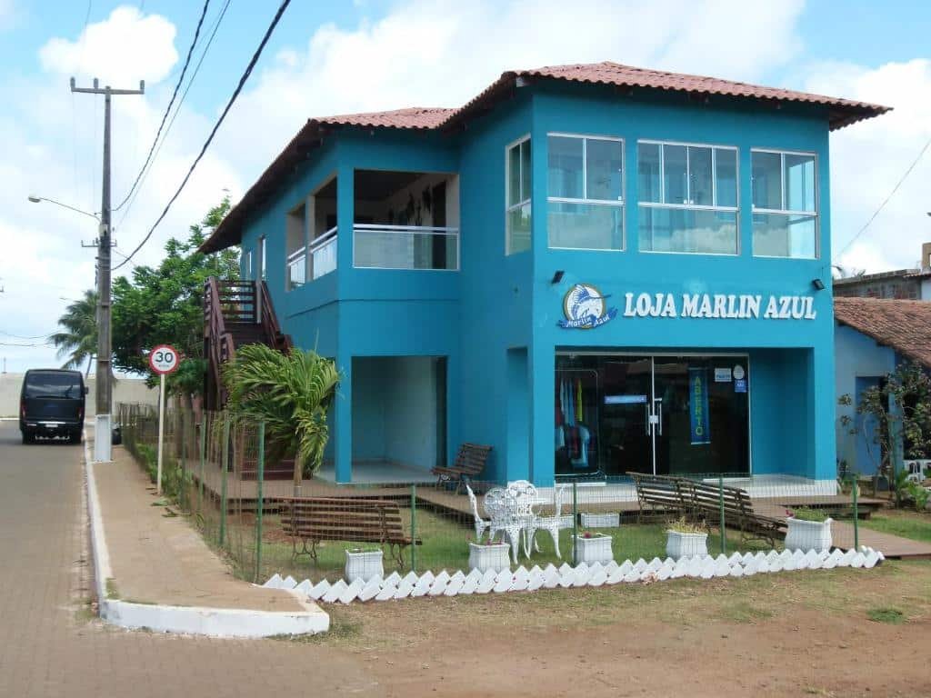 Fachada azul da Pousada Marlin Azul, em Fernando de Noronha, com os dizeres "Loja Marlin Azul" e a logo do local bem em frente. A construção está numa esquina.