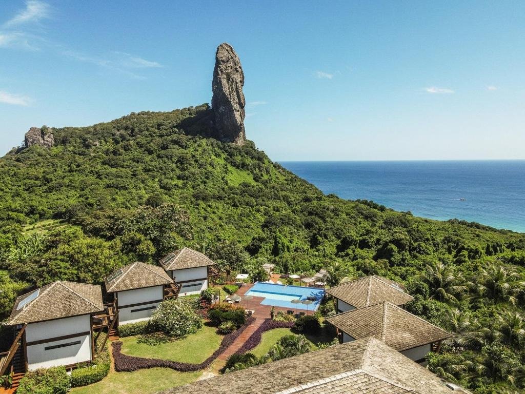 Vista do Morro do Pico e do mar de Fernando de Noronha a partir da Pousada Morena, com bangalôs charmosos e uma piscina ao ar livre, envoltos pela vegetação da ilha