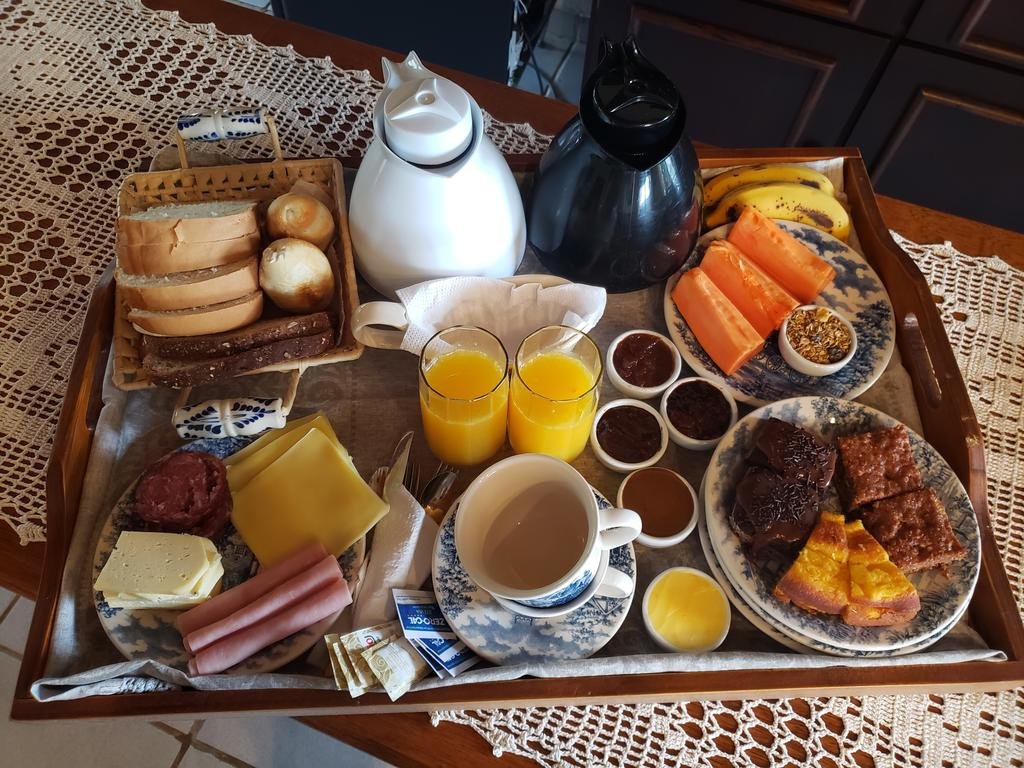 Bandeja de café da manhã na Pousada Rural Vista Alegre com frutas, pães, bolos, sucos, cafés e mais itens.