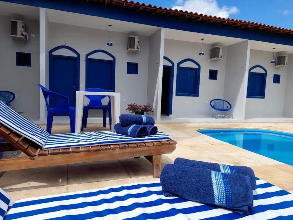 Área da piscina, com cadeiras, espreguiçadeiras e varanda de alguns quartos da Pousada Vila de Charme