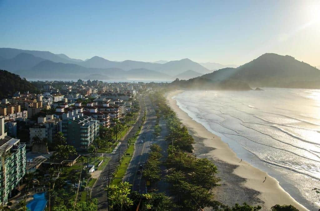 Praia Grande em Ubatuba sob uma vista aérea, a principal avenida, logo em seguida a faixa de areia e o mar, do outro lado da avenida, as pousadas e hotéis na Praia Grande de Ubatuba