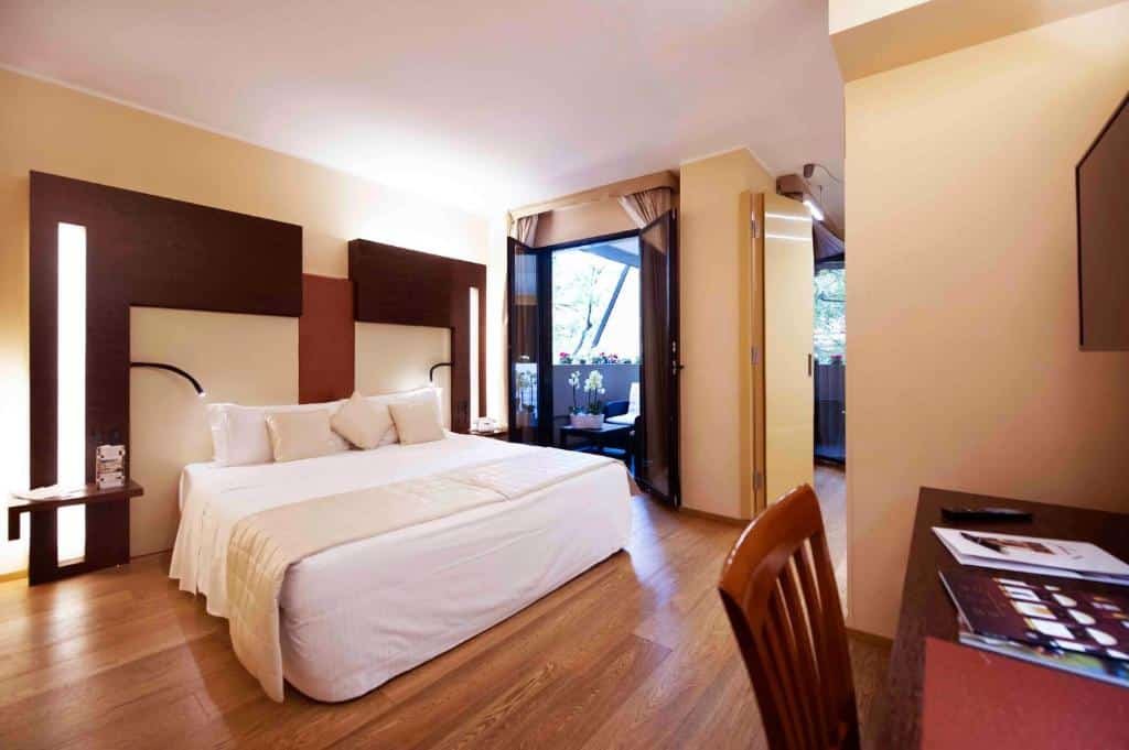 quarto com cama de casal, escrivaninha e cadeira de madeira com porta para a sacada no Art Hotel Navigli