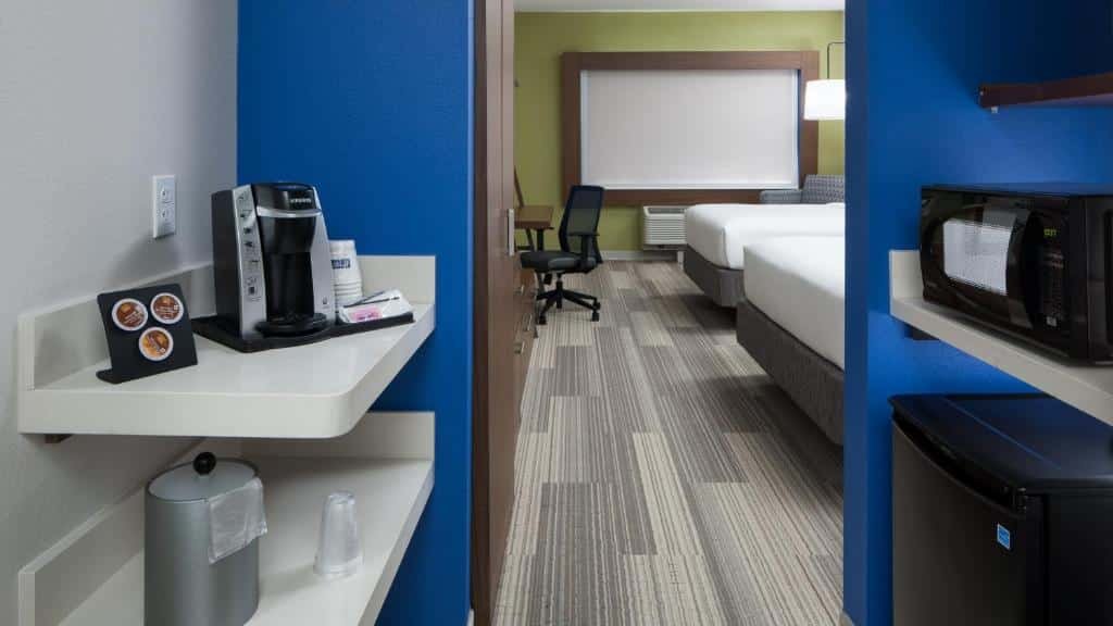 quarto com cafeteira com copos e micro-ondas, balcão com cadeira e duas camas do Holiday Inn Express & Suites - Orlando At Seaworld, an IHG Hotel