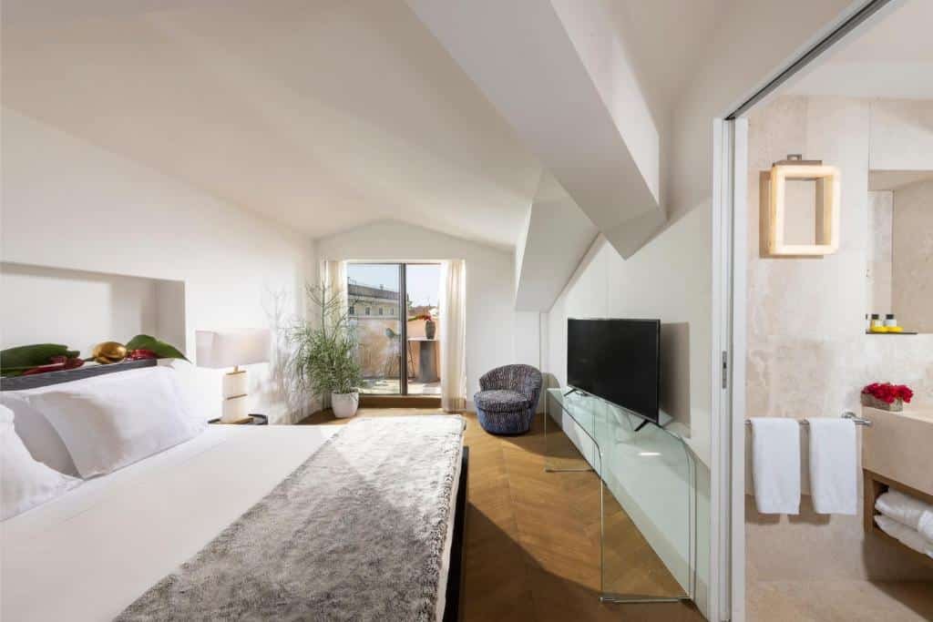 quarto do Hotel Palazzo Manfredi, um dos hotéis de luxo em Roma, com cama enorme, tv em frente, poltrona e varanda com vista da cidade