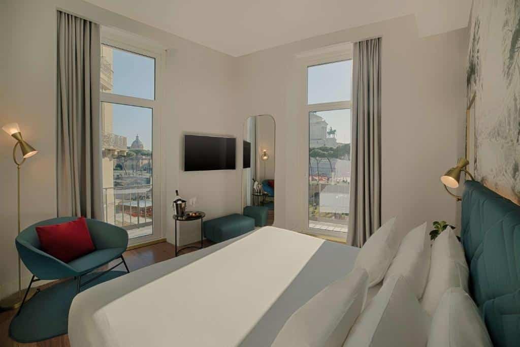 quarto do NH Collection Roma Fori Imperiali, um dos hotéis de luxo em Roma, com cama grande, tv com poltronas esverdeadas e espelho com duas janelas, uma em cada parede, com vista para o Fórum Romano