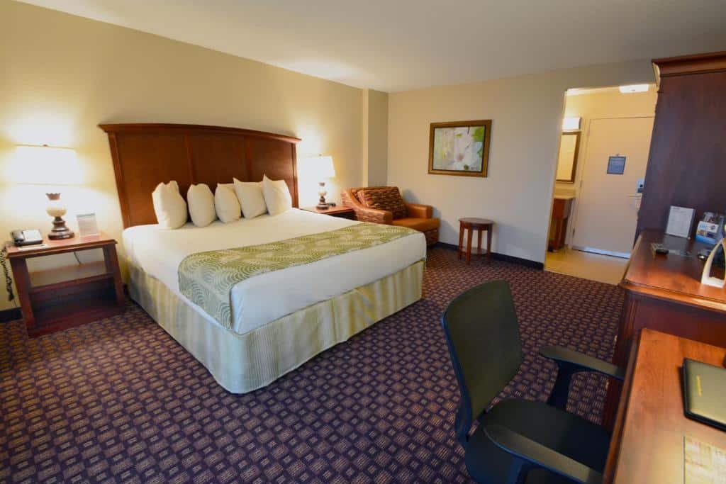 quarto amplo do Rosen Inn Closest to Universal com cama de casal grande com luminárias em ambos os lados, mesa com cadeiras, carpete e mesa de escritório com balcão