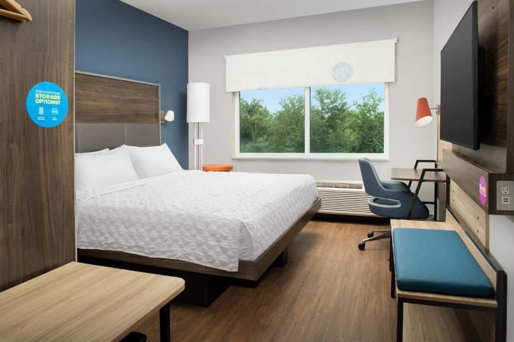 quarto com cama de casal, janela dupla com vista para vegetação, cadeira e tv do Tru By Hilton Orlando Convention Center, um dos hotéis em Orlando