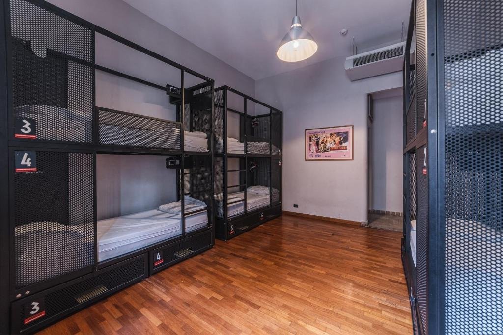 quarto do YellowSquare Rome, um dos hostels em Roma, com chão que imita madeira, beliches com gradinhas e lugares para guardar os itens de cada um