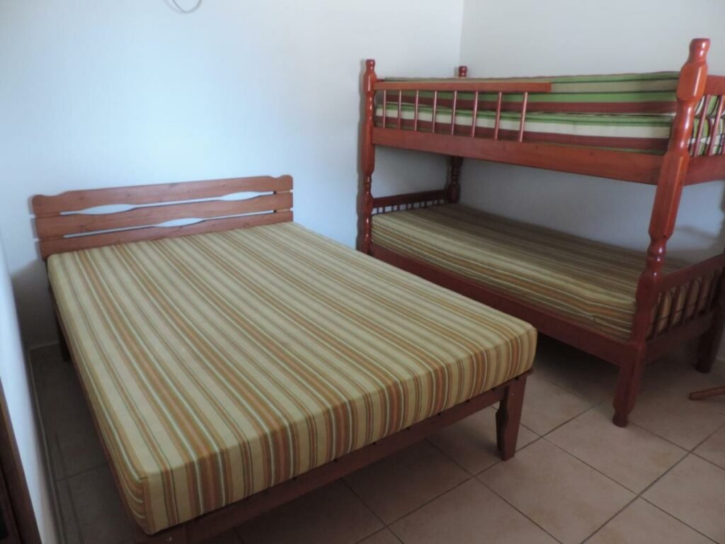 Quarto da Casa Orquídeas Ubatuba Praia da Lagoinha com cama de casal do lado esquerdo da imagem e do lado direito uma beliche.