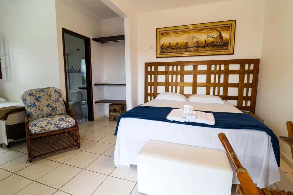 Quarto em HOTELARE Bóra Morá Pousada, uma cama de casal, uma cama de solteira, uma cadeira, um banheiro, um buff branco, um quadro sob a cama, algumas prateleiras