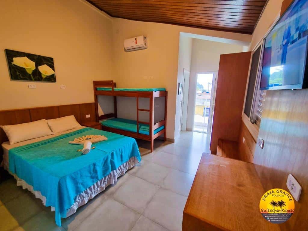 Quarto do Pousada Praia Grande Hostel, um local amplo com uma cama de casal, uma beliche, um armário, um quadro sob a cama, ar-condicionado e uma televisão