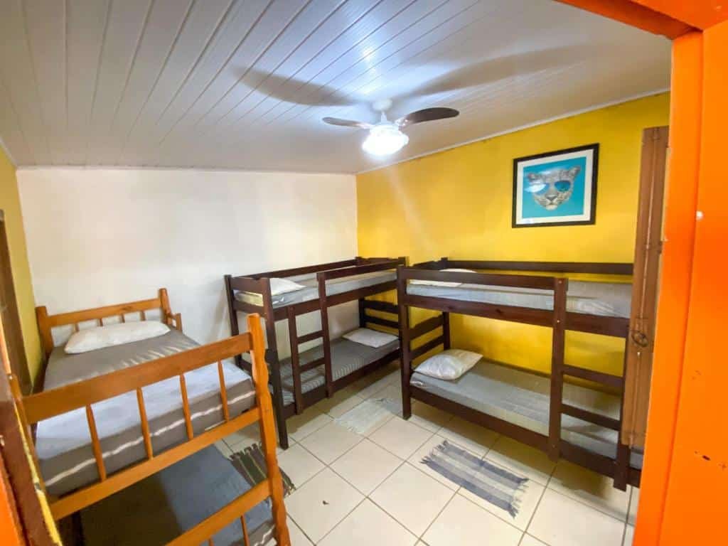 Quarto compartilhado no Sintonia Surf Hostel e Bar com três beliches e um ventilador de teto