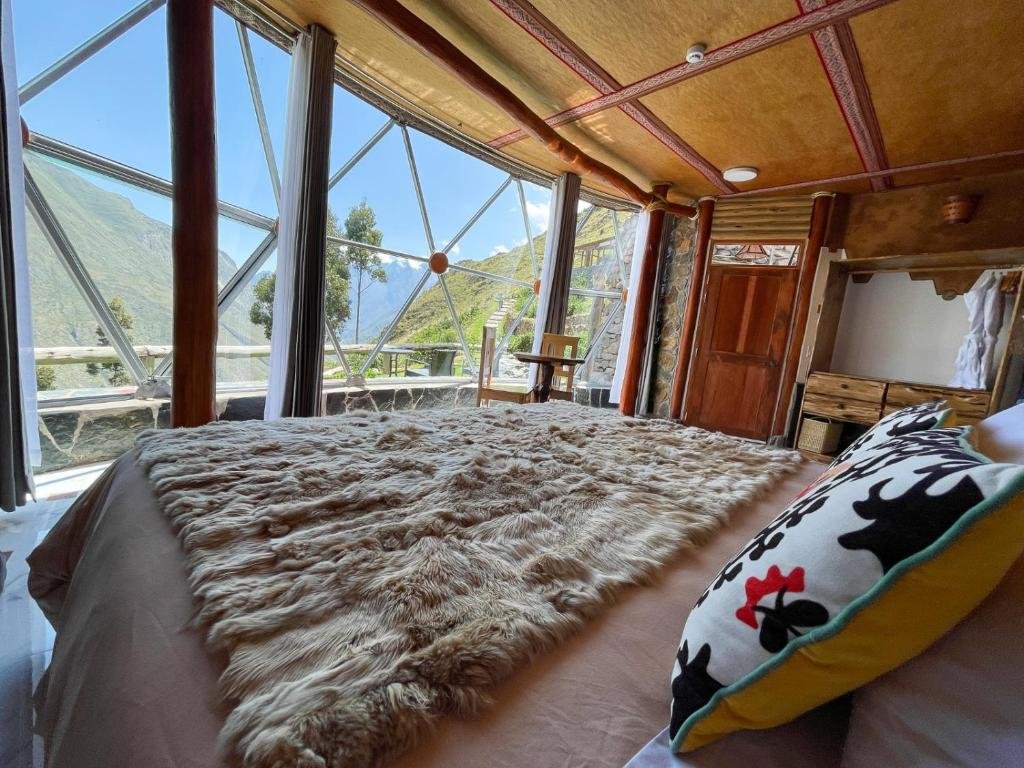 quarto do stardomelogde com uma cama de casal com vista para as montanhas, no lado esquerdo do quarto, com paredes totalmente de vidro