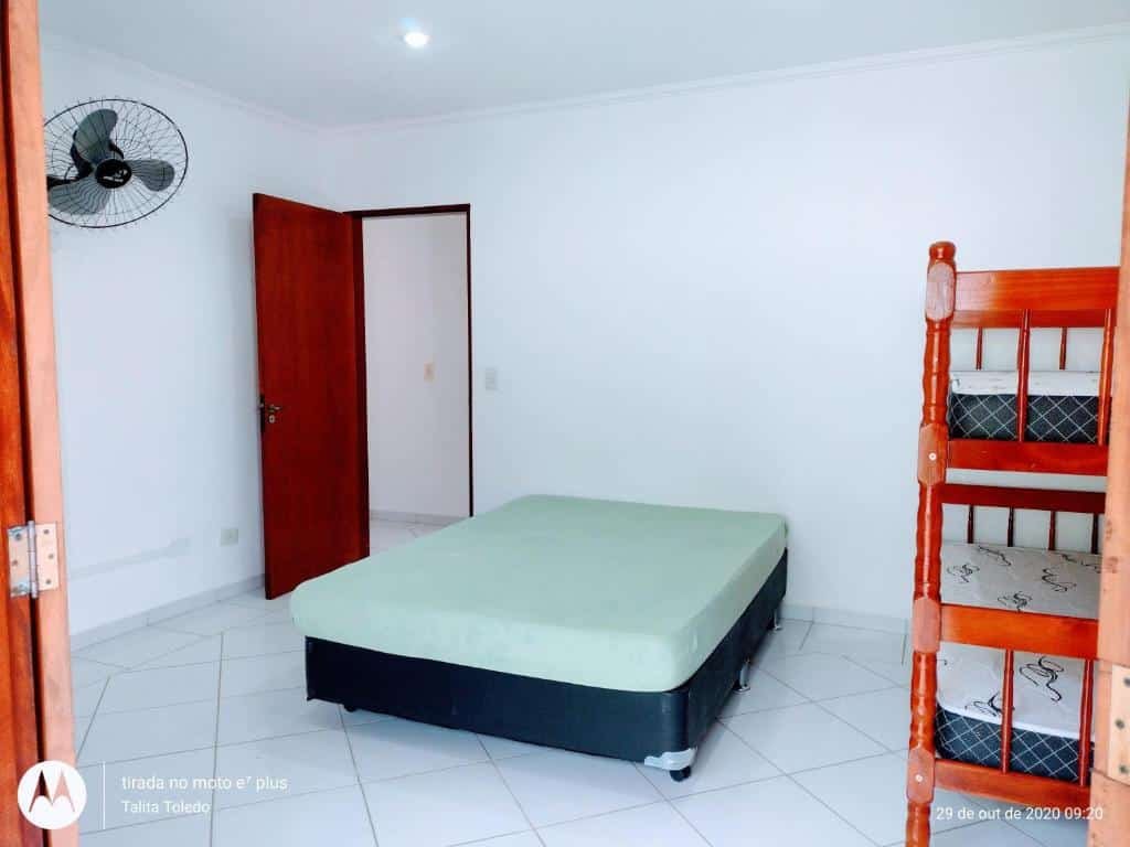 Quarto do Recanto Canoa Pequena. Uma cama de beliche do lado direito, no meio uma cama de casal, no lado esquerdo a porta do quarto e um ventilador em cima. Foto para ilustrar post sobre airbnb em Perequê Mirim.