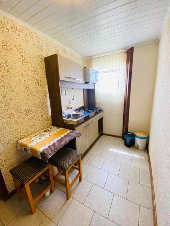 Cozinha do RESIDENCIAL BORGES CANELA. No canto inferior esquerdo há uma pequena mesa com duas cadeiras, e na sua frente está uma mini cozinha.