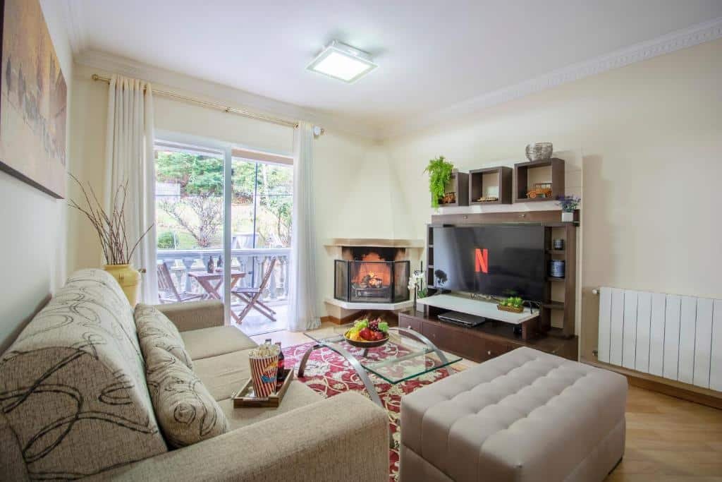 Sala de estar do Residencial Chateau du Loire com sofás, lareira, televisão e uma varanda com duas cadeiras e uma mesa