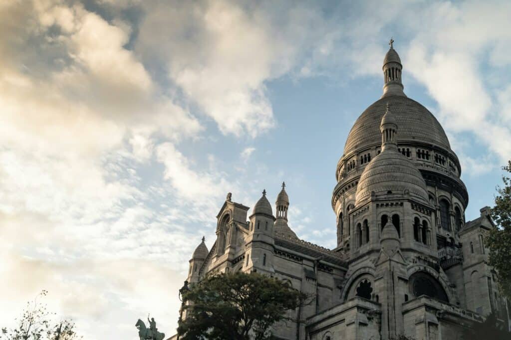 Basílica de Sacré-Coeur vista de baixo com o céu azul ao lado. Esse é um dos pontos turísticos de Paris.