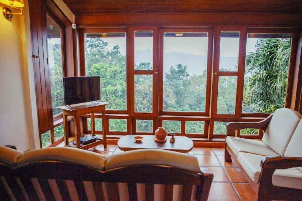 Sala de estar do Refúgio Toque Toque Chalés com sofá a frente uma mesa de centro e ao fundo do lado esquerdo da imagem uma cômoda com TV.