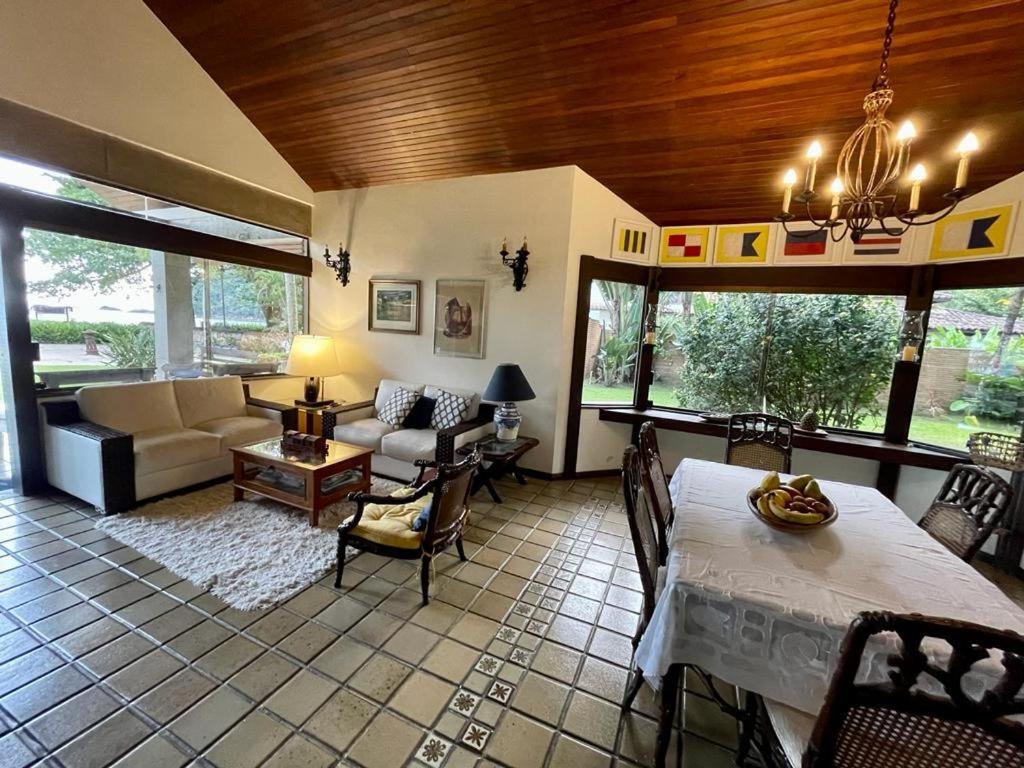 Sala de estar da Guaeca Villa com sala de estar do lado esquerdo da imagem com sofá, poltrona e mesa de centro já do lado direto uma mesa de jantar.