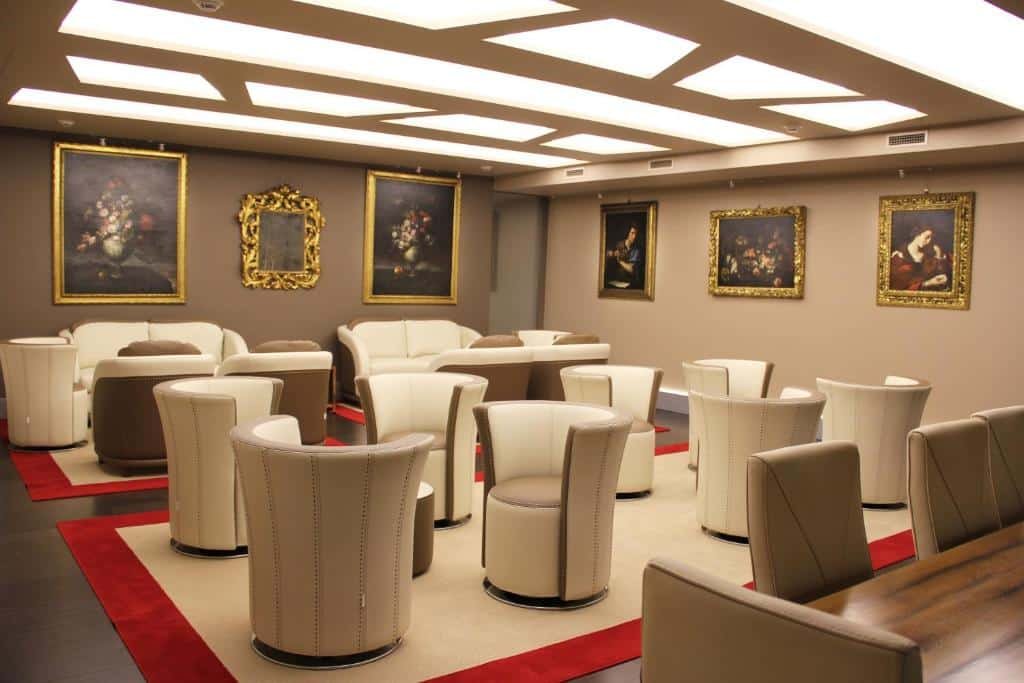 salão com poltronas altas e mesinhas redondas com obras de arte nas paredes no Harry