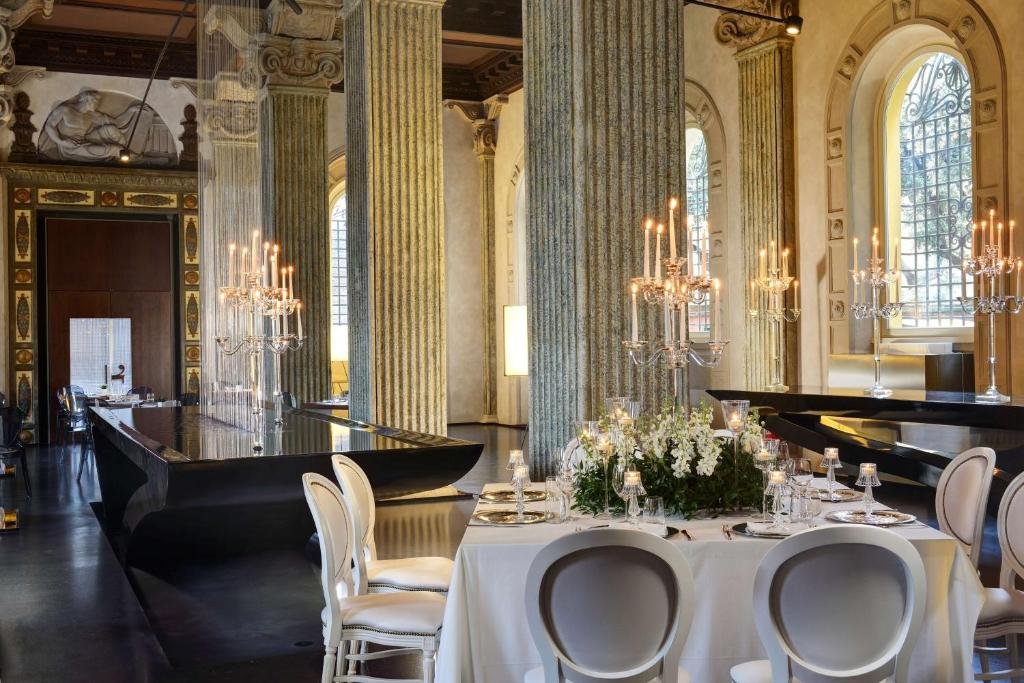 salão do Palazzo Montemartini Rome com detalhes clássicos, mesas e cadeiras com candelabros e lustres em mesas compridas de pedra e colunas trabalhadas
