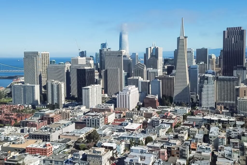 Vista geral dos prédios e casas de San Francisco. Ao fundo é possível ver um pedaço do mar e da ponte.