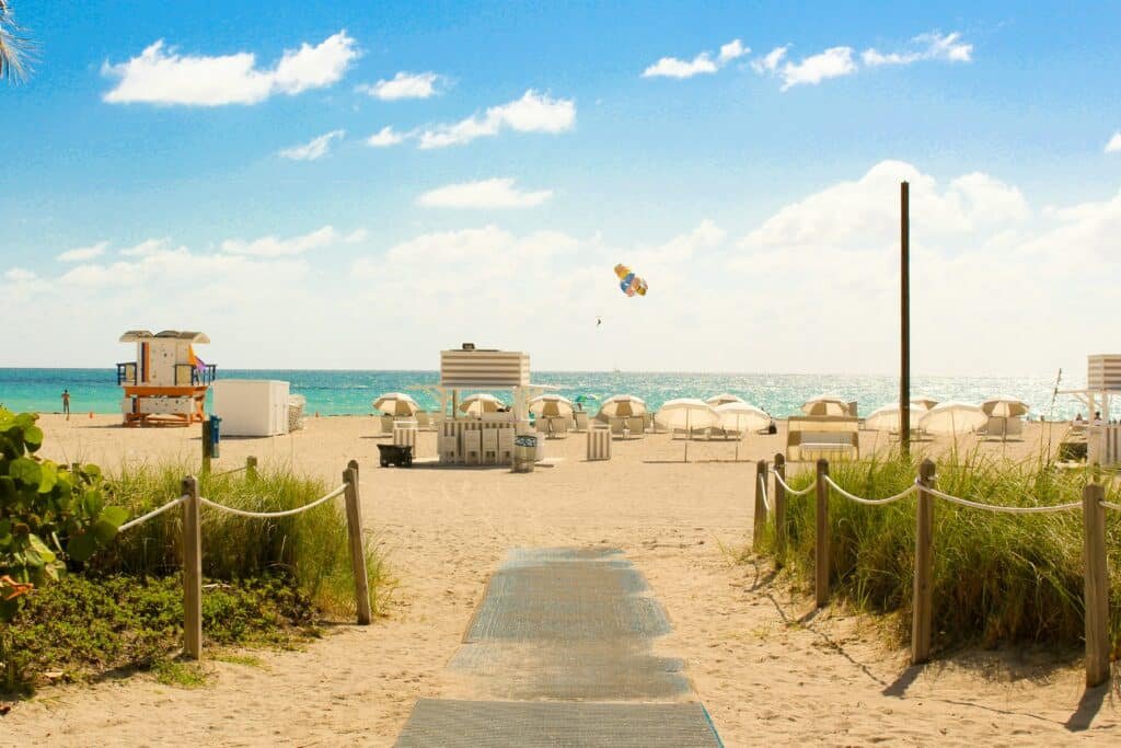Praia de South Beach. A imagem mostra a faixa de areia com vários guarda-sóis, a casa do salva-vidas e o mar logo em frente.