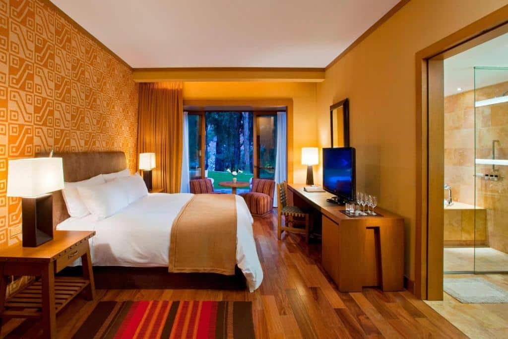 suíte do Tambo del Inka, a Luxury Collection Resort & Spa, Valle Sagrado com uma cama de casal à esquerda do quarto, uma varanda com portas duplas que dão acesso ao jardim e uma porta à direita que dá acesso ao banheiro com banheira